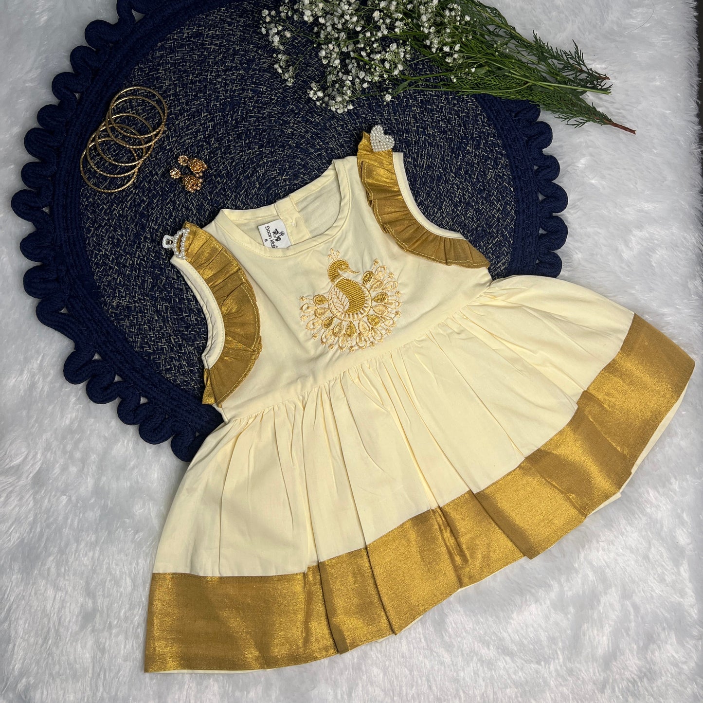 Beige and gold dress with floral peacock decoration on a textured surface