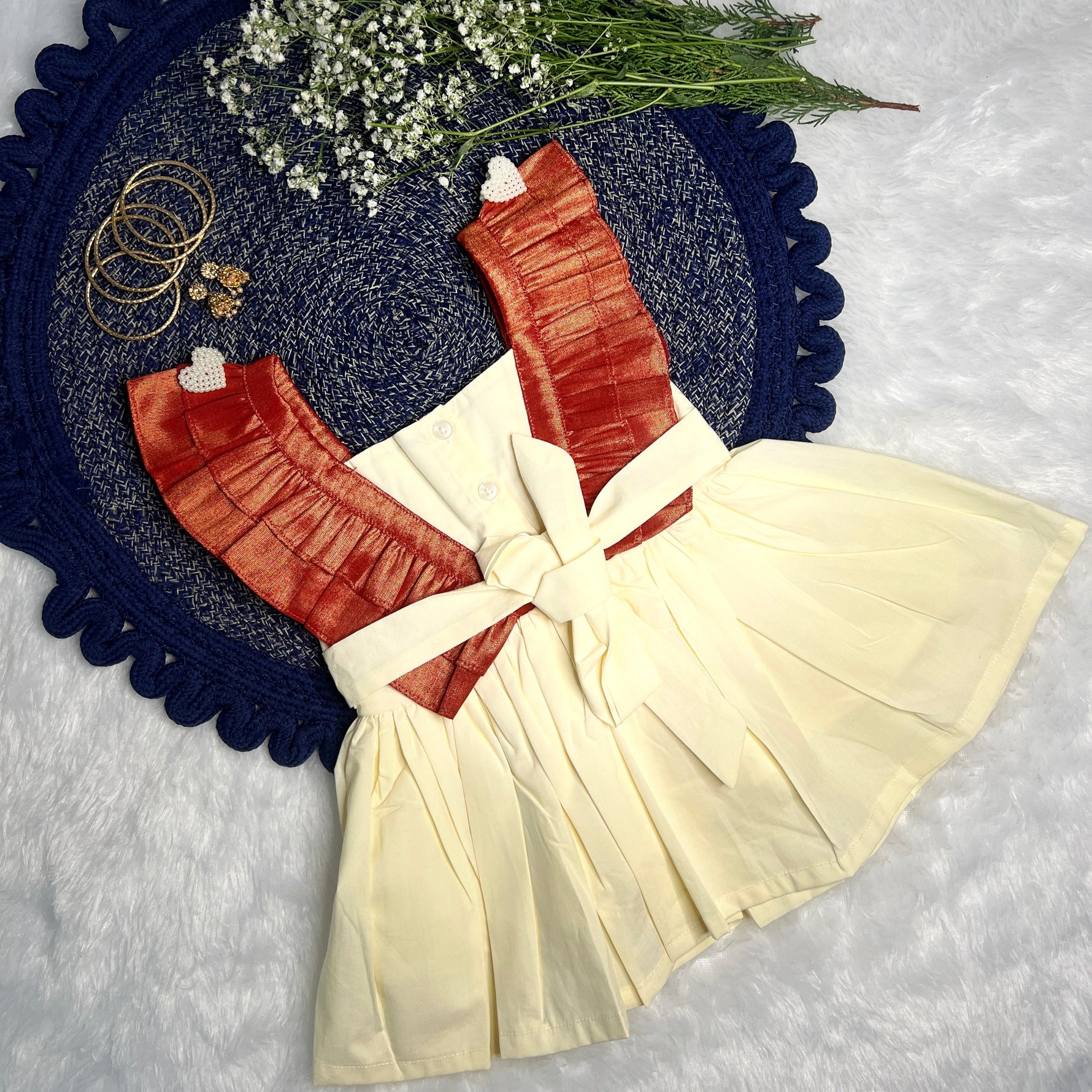 ethnic dress with a bow, flowers, and jewelry on a textured surface