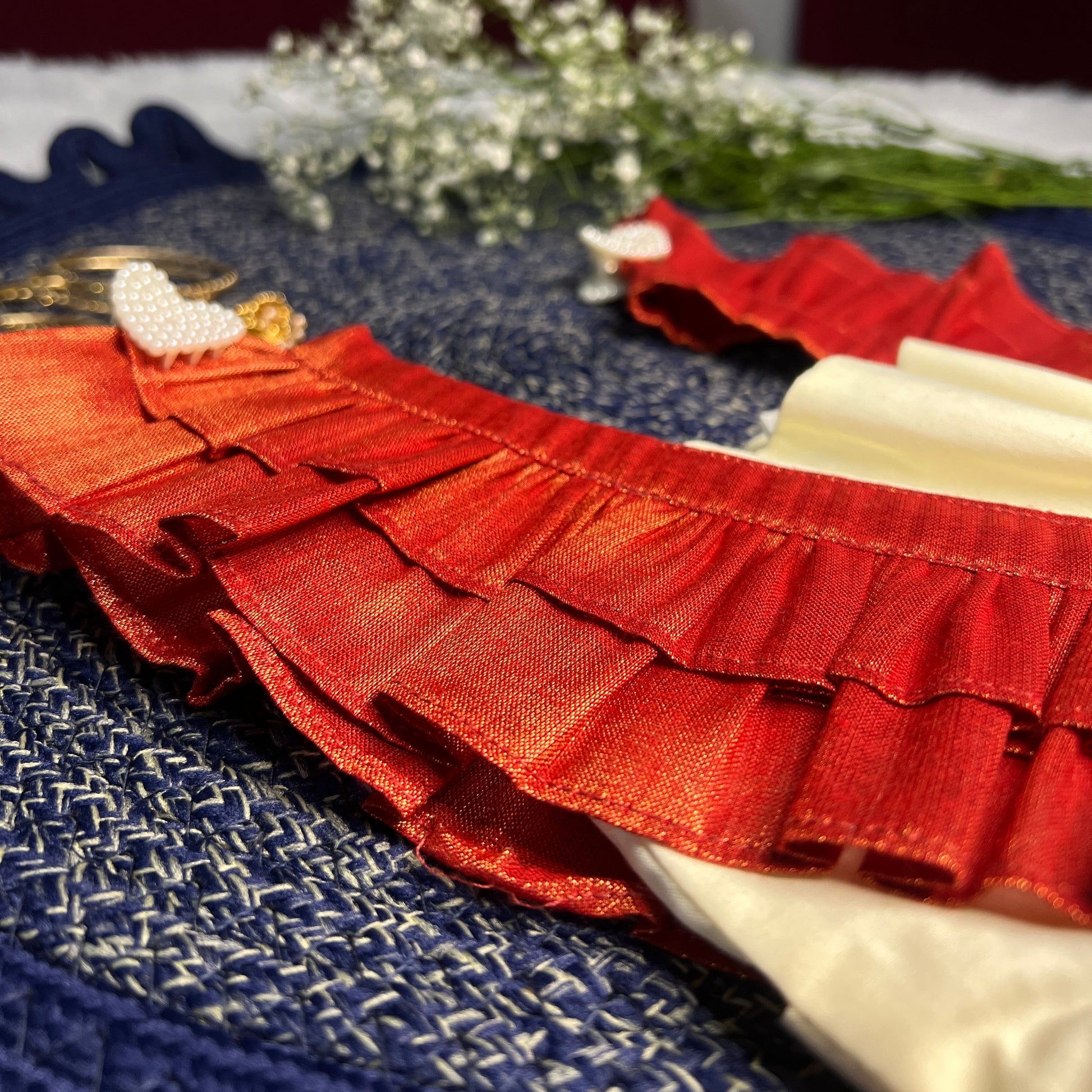 Red ruffled dress on a blue textured surface with white flowers in the background
