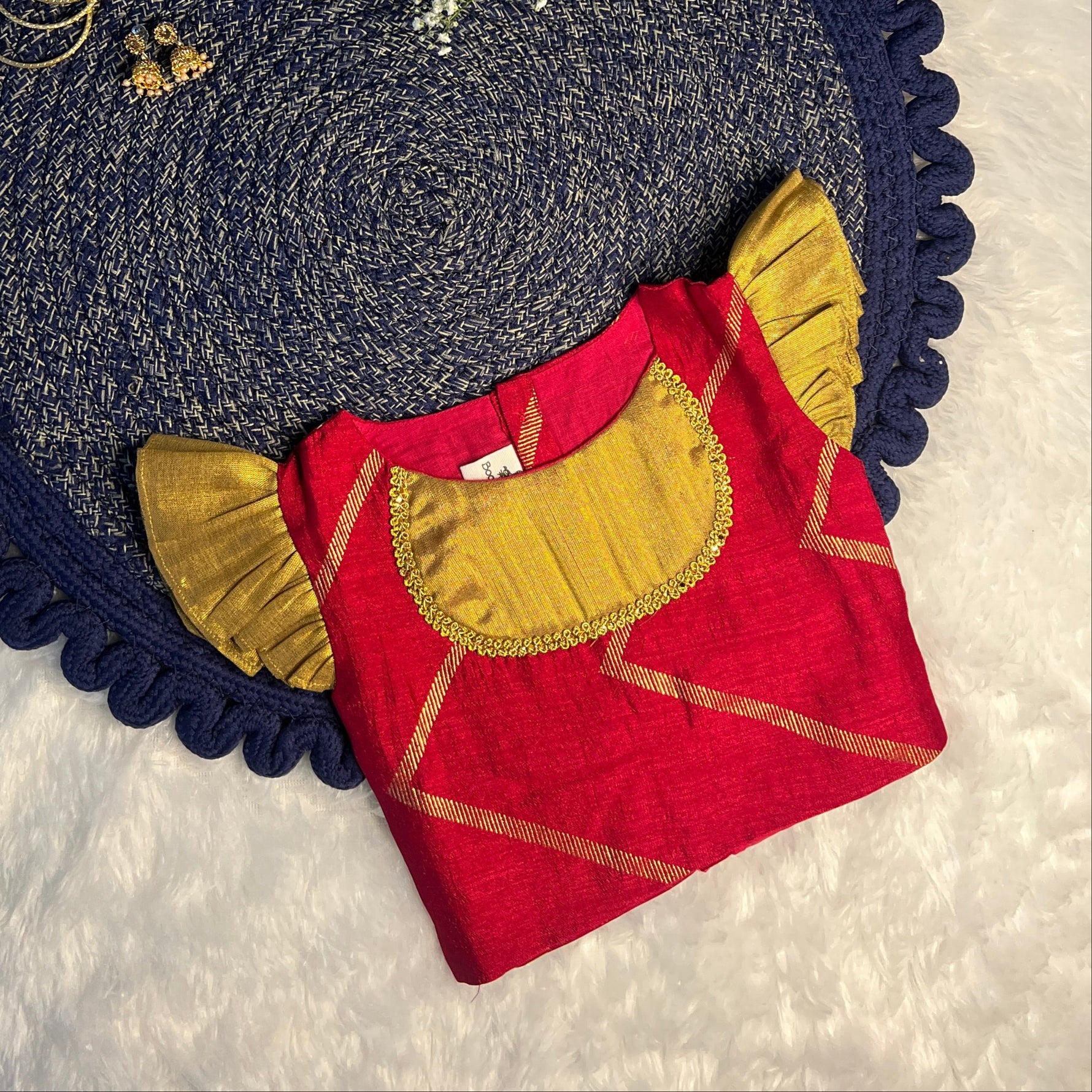 red and gold top girl dress, navy border, and white flowers on a textured white background