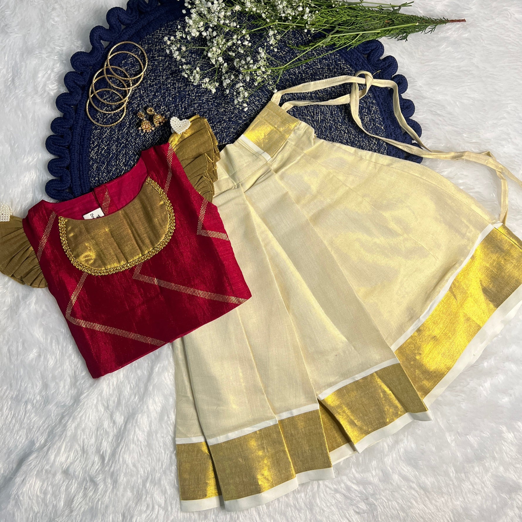 traditional girl skirt and top with gold and red details on a textured surface.