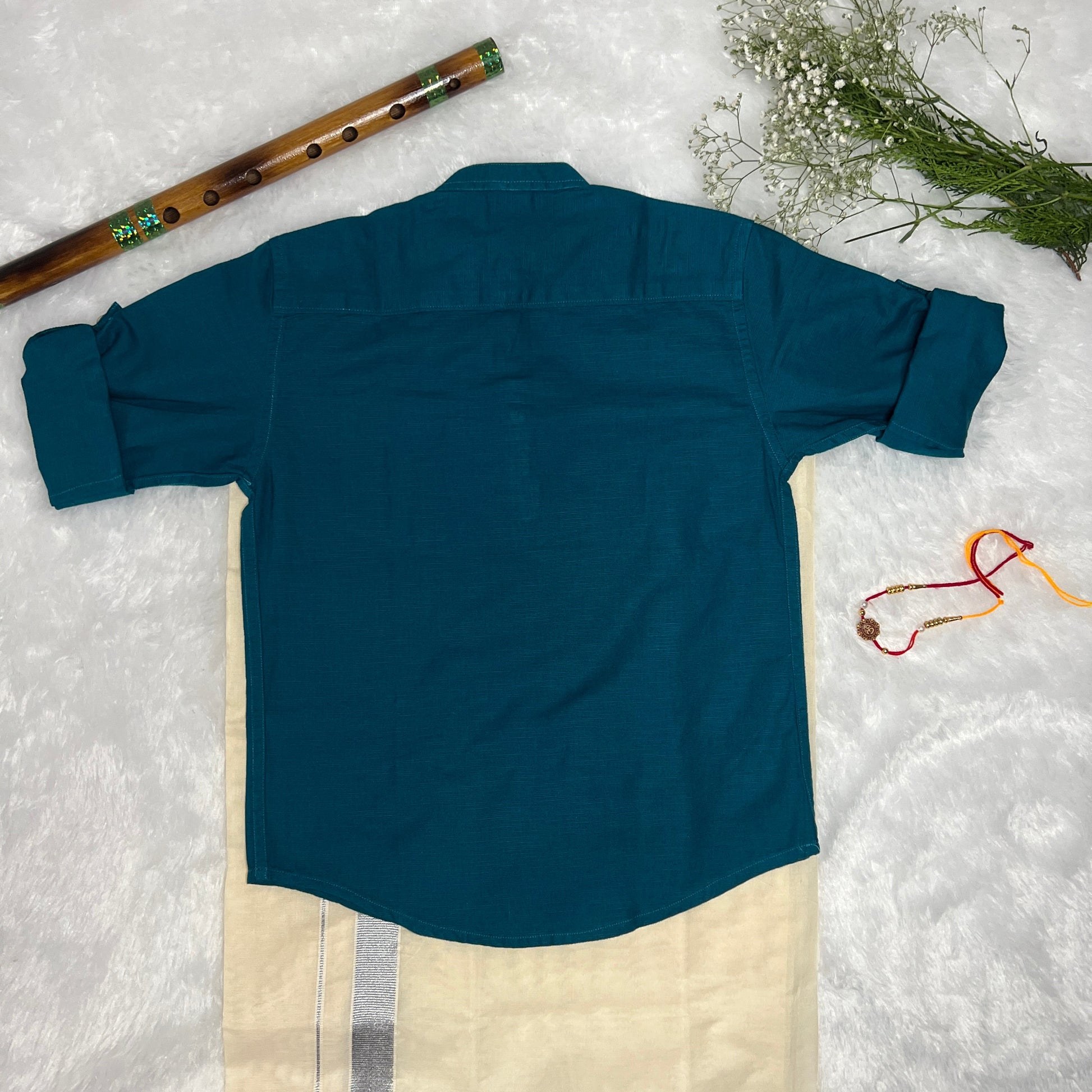 Blue shirt with white dhothi on a textured white surface with decorative elements