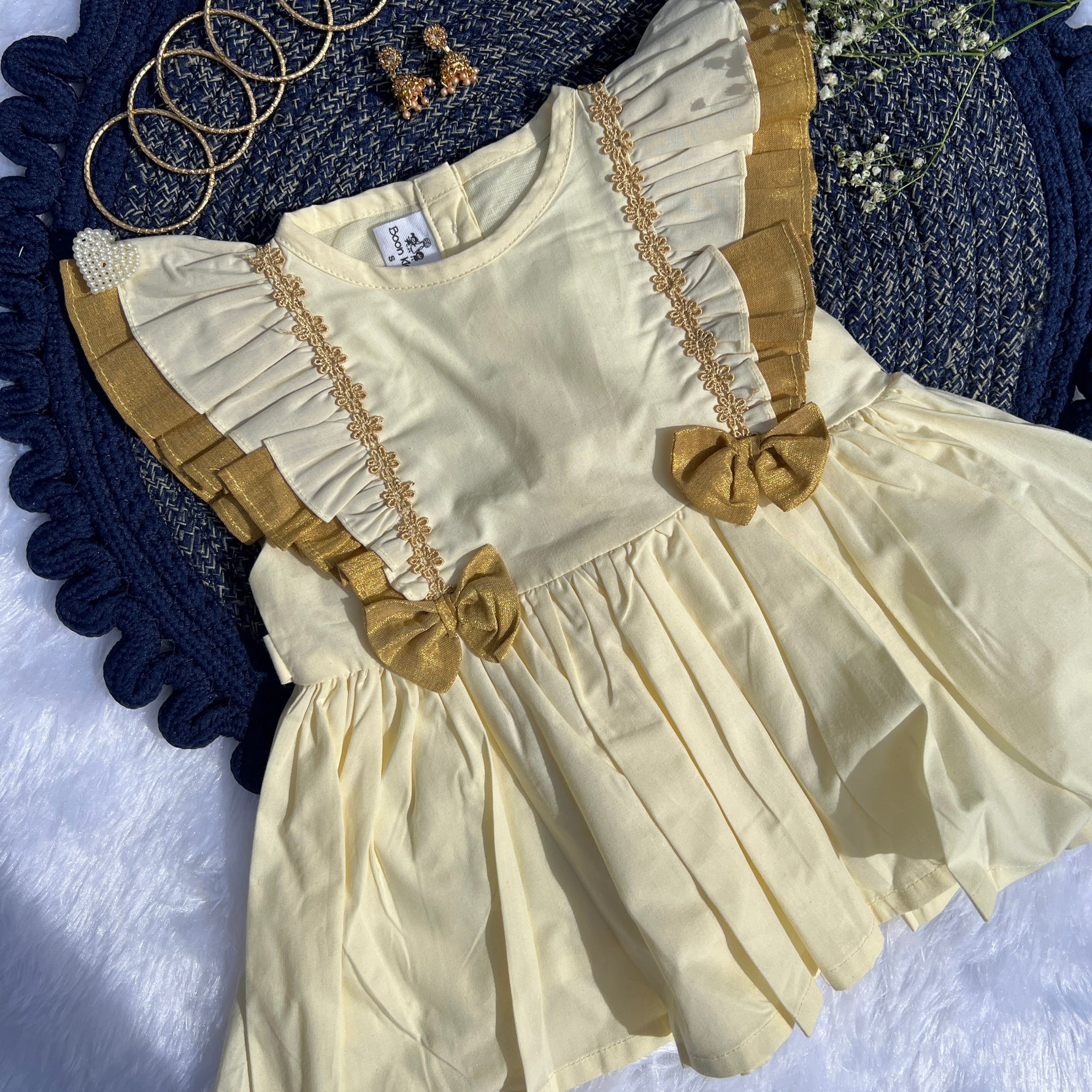 Yellow dress with ruffled details on a textured blue and white surface.