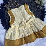 White and gold dress with matching vest on a textured blue surface.