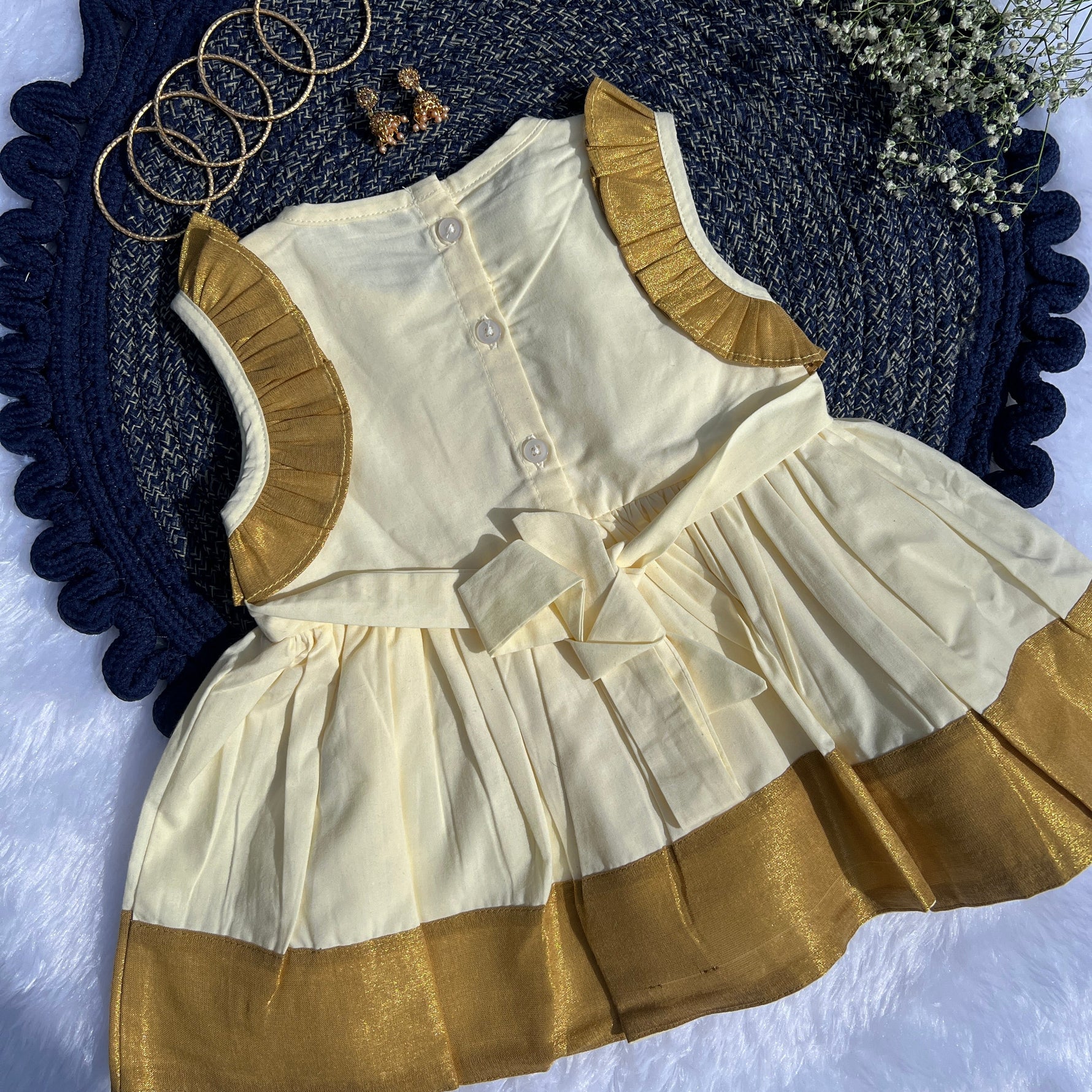 White and gold dress with matching vest on a textured blue surface.