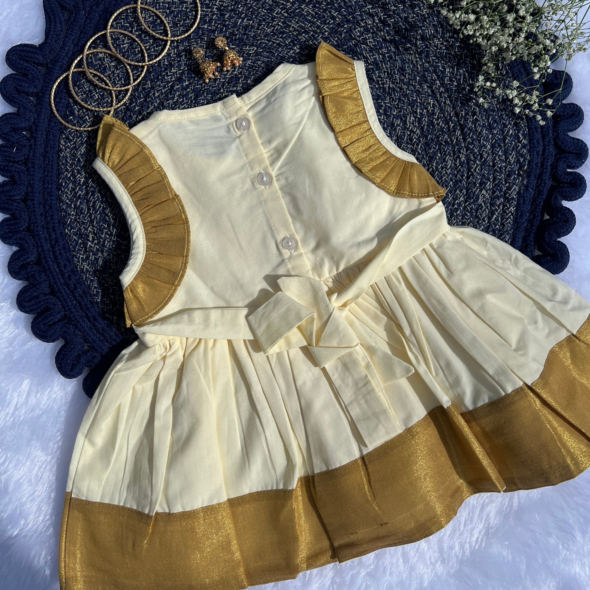 White and gold dress with matching vest on a textured blue surface.