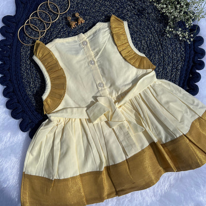 White and gold dress with matching vest on a textured blue surface.