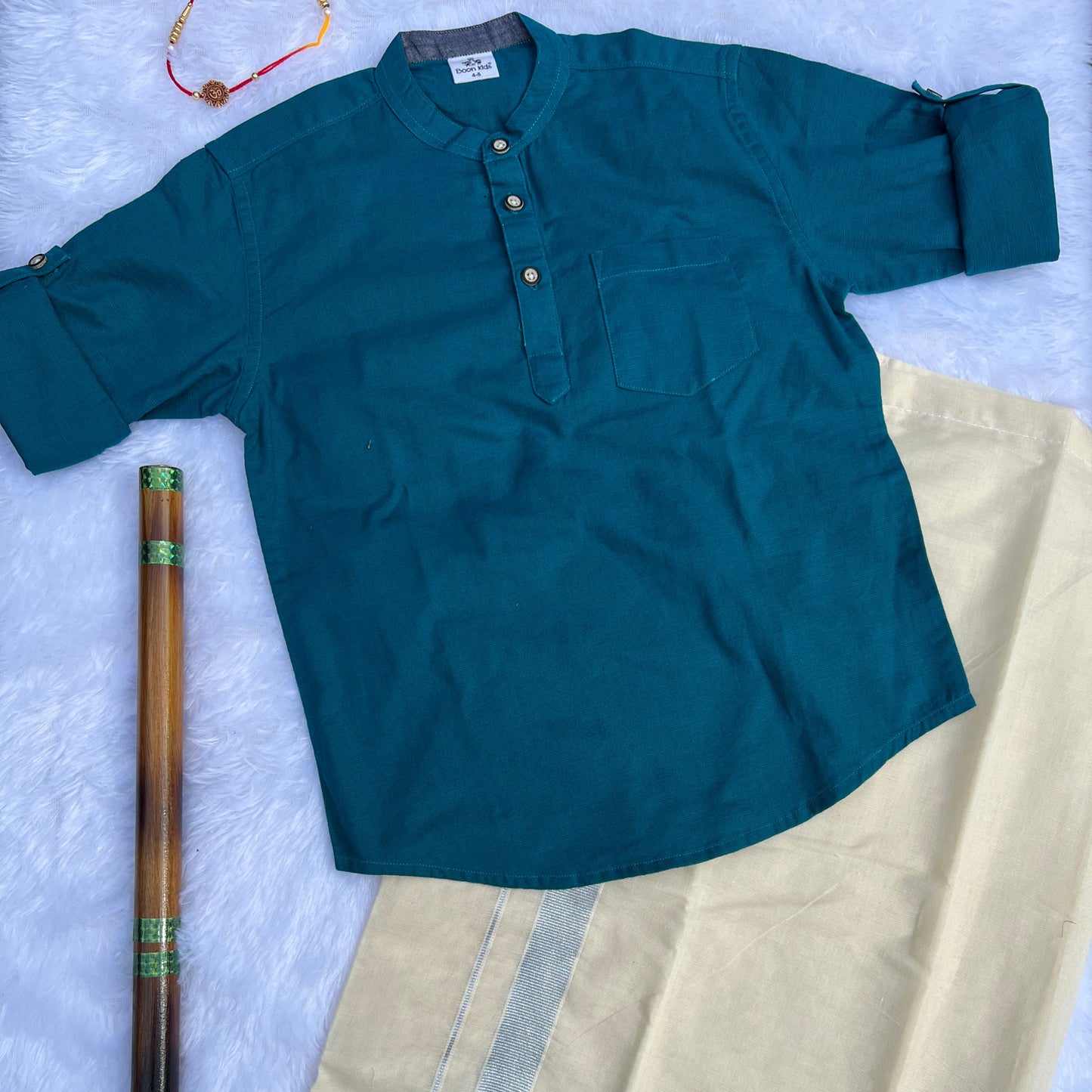 Teal shirt on a light fabric background with a wooden object.
