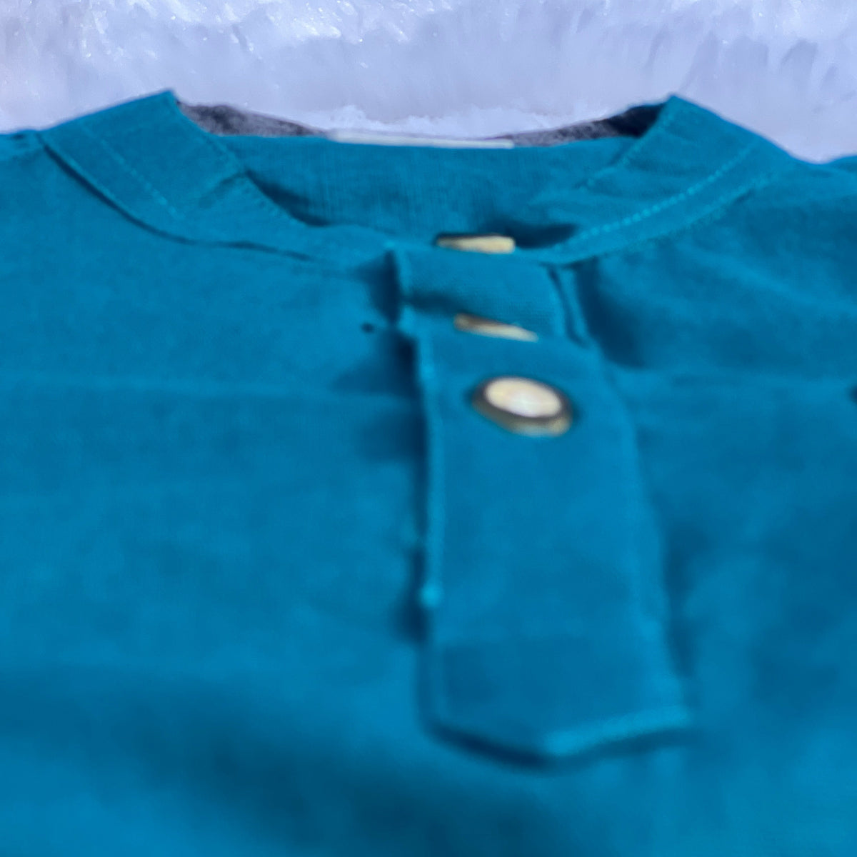 Teal shirt with buttons on a blurred background