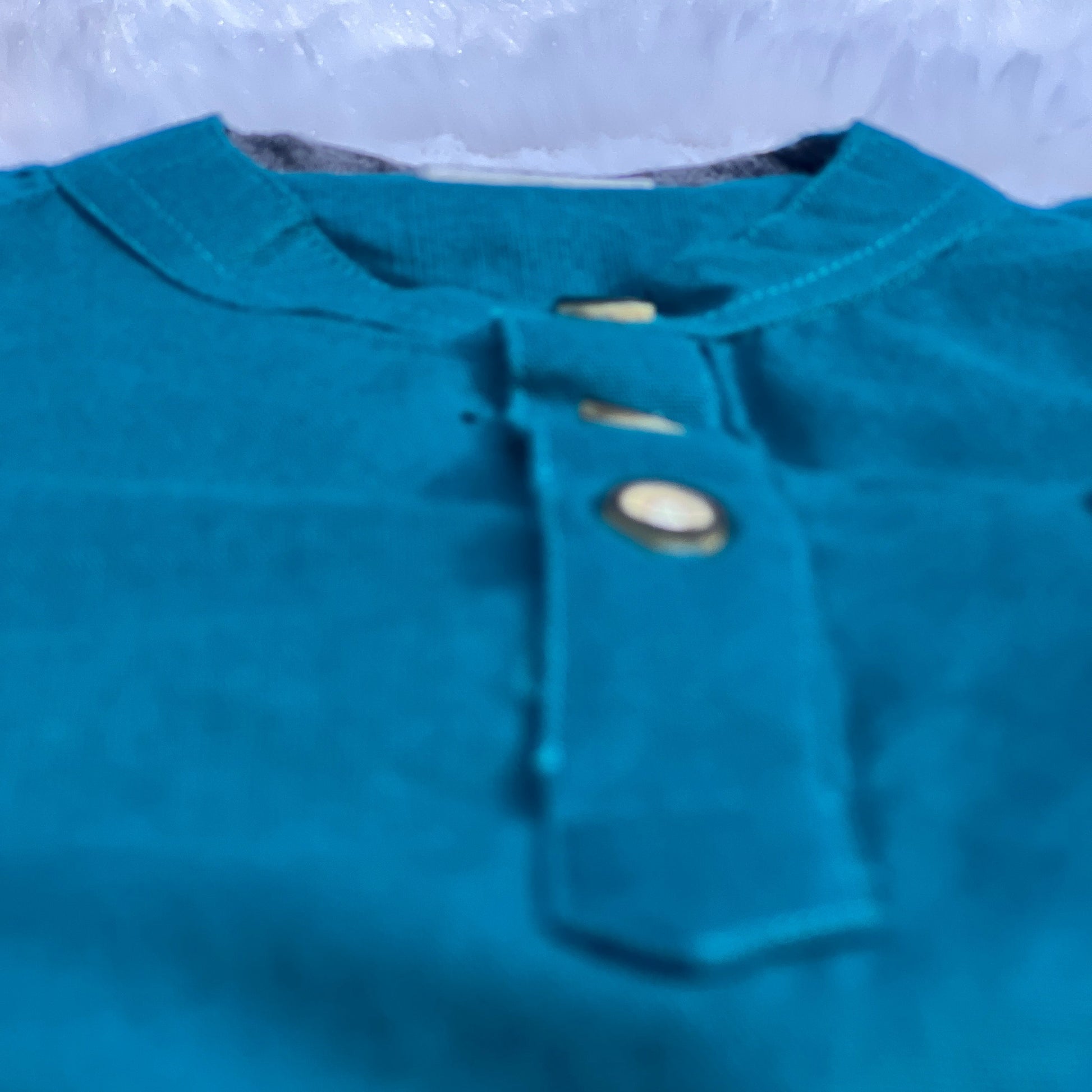 Teal shirt with buttons on a blurred background