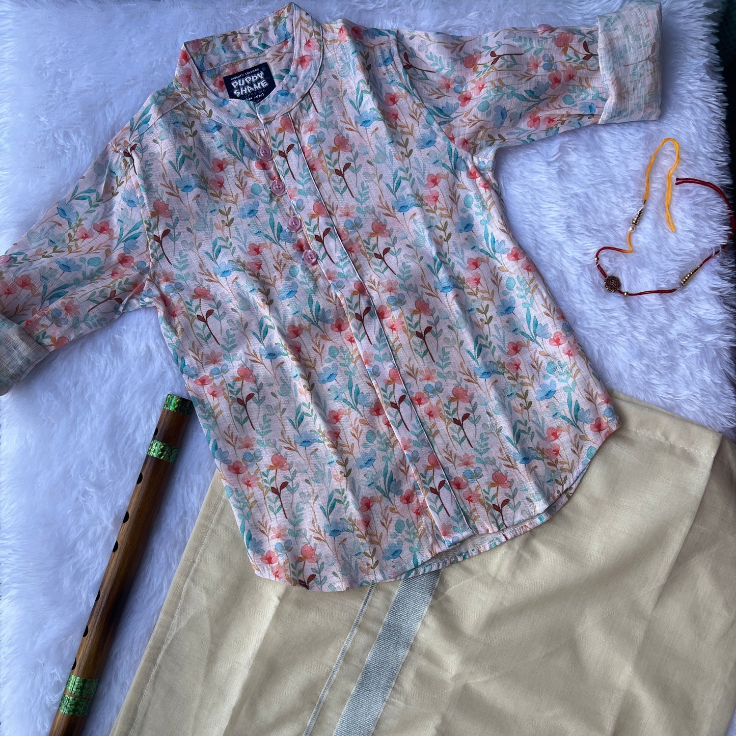 Floral-patterned shirt and a dhoti on a textured surface with a flute