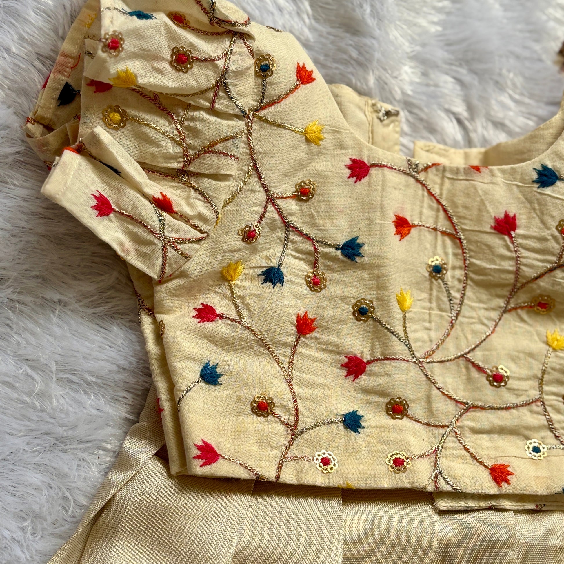 Beige embroidered fabric with colorful patterns on a white textured background