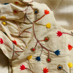Close-up of embroidered fabric with colorful floral patterns on a beige background