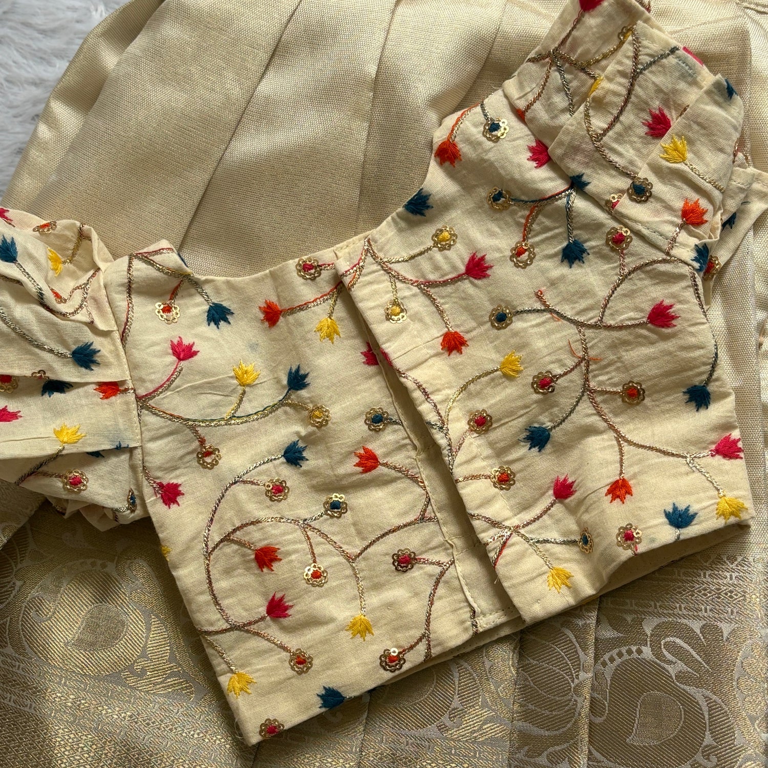 Beige embroidered fabric with colorful patterns on a textured beige background