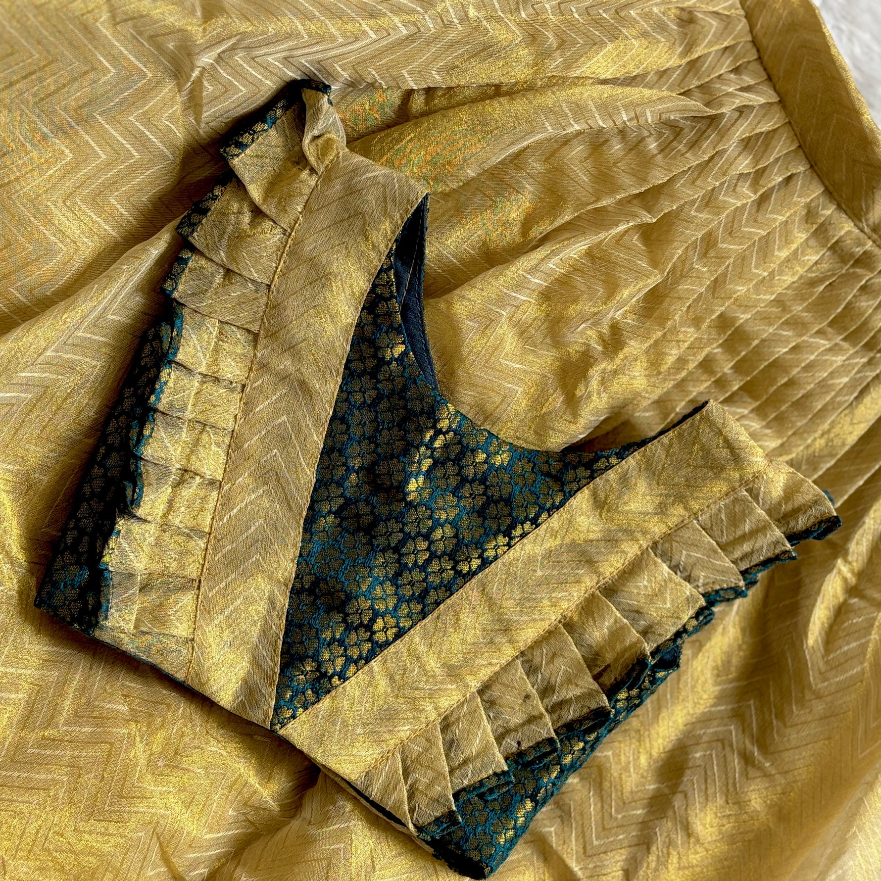 Close-up of a green top with gold skirt with intricate patterns baby dress
