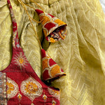 Decorative ethnic dress with red and yellow patterns on a textured beige background