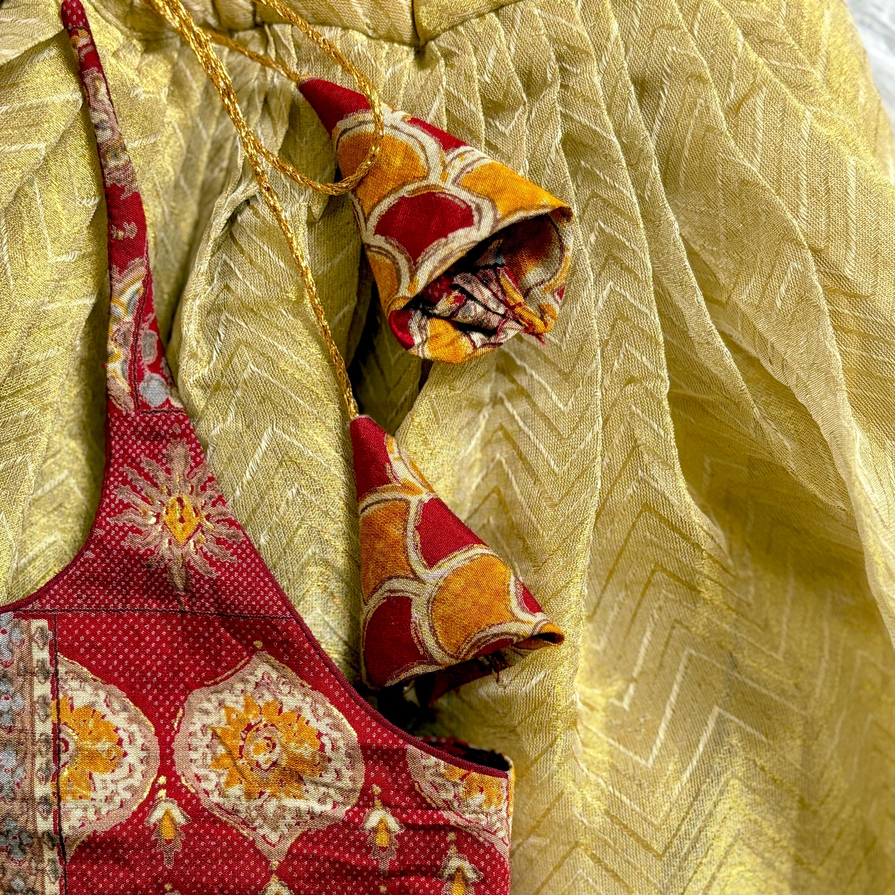 Decorative ethnic dress with red and yellow patterns on a textured beige background