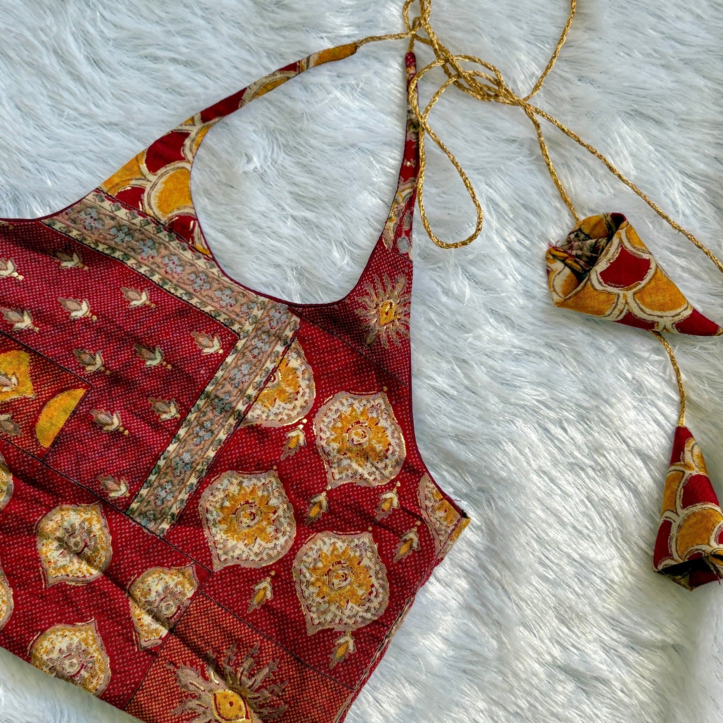 Red patterned fabric with gold accents on a white textured background