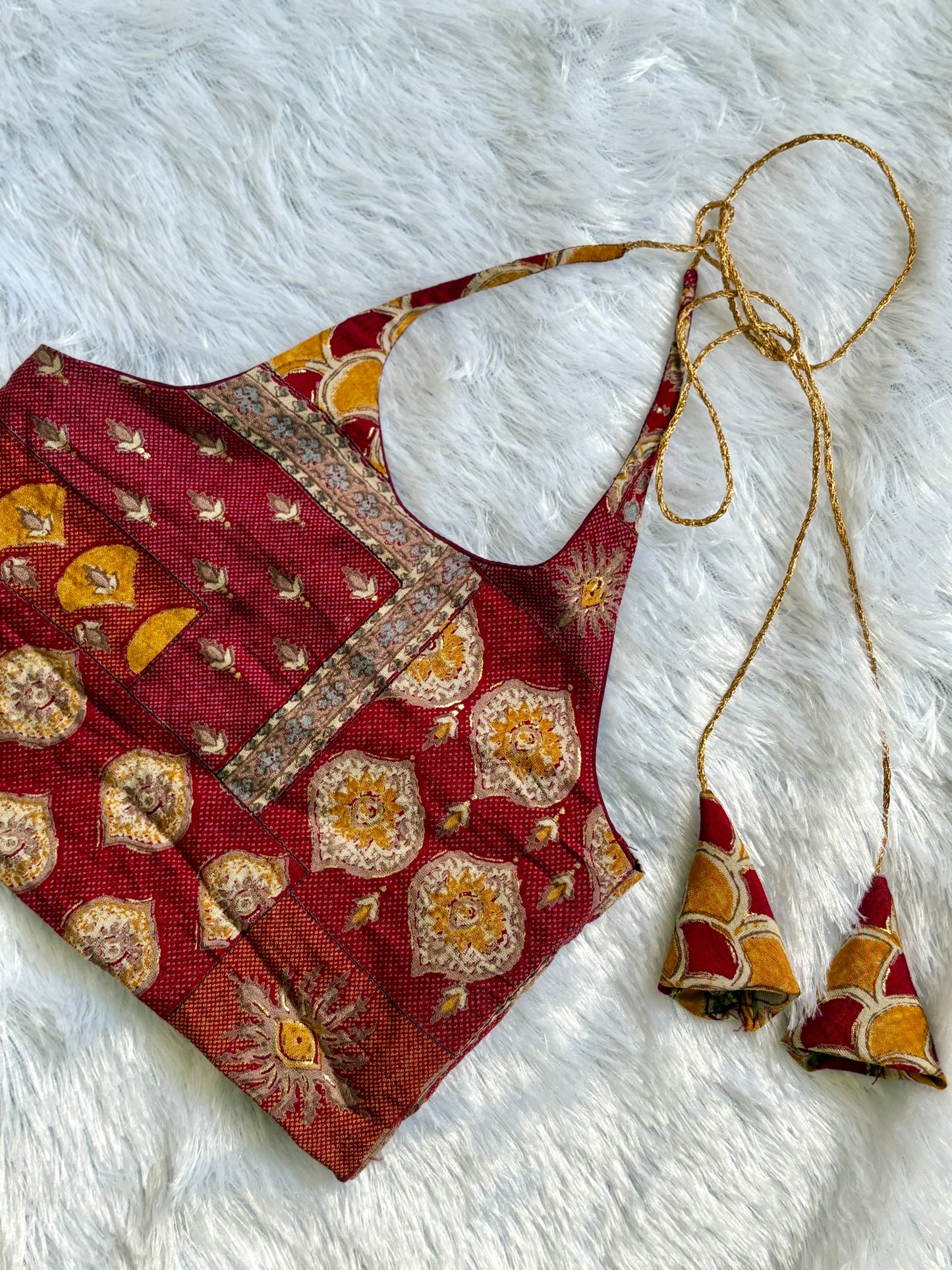 Red patterned blouse with matching earrings on a white textured surface